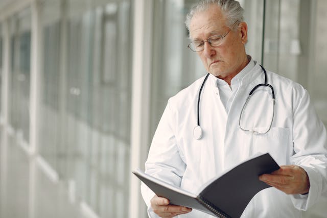 Experienced doctor in a white coat reviewing medical records in a modern hospital corridor, representing Israel's world-class healthcare and advanced medical tourism services.